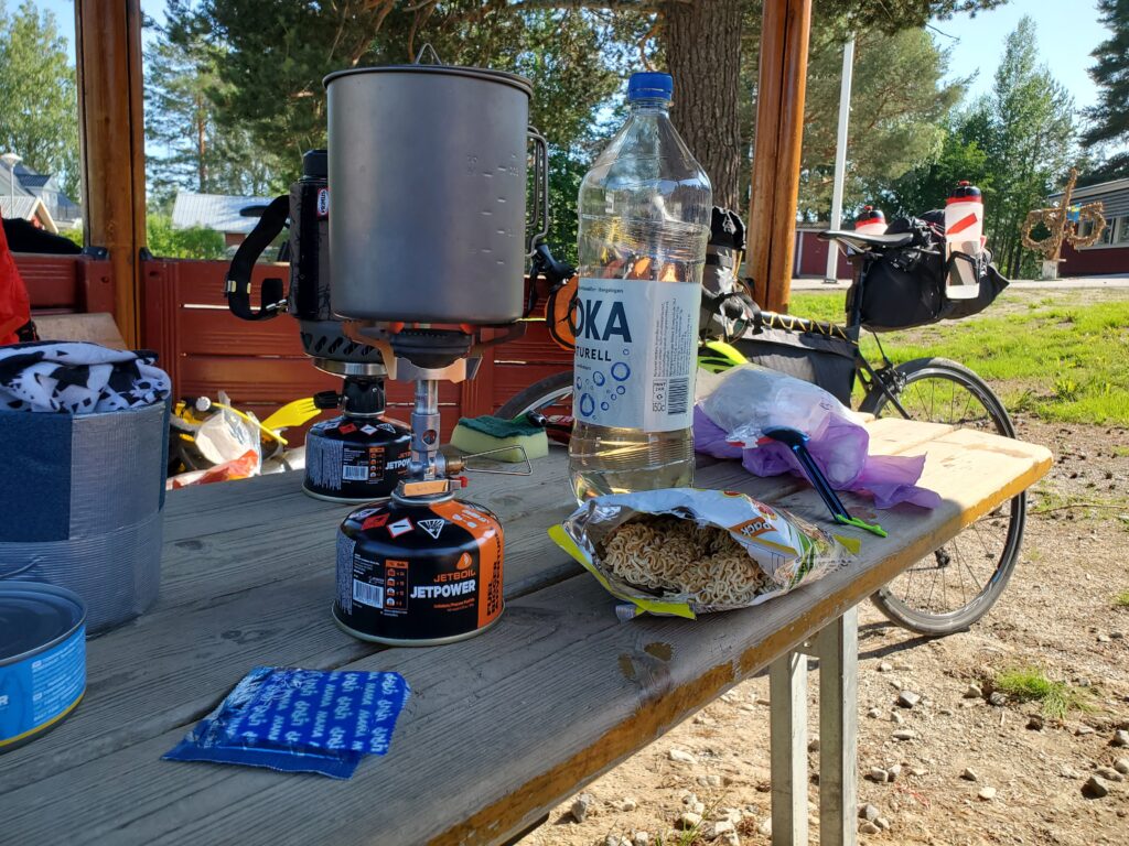 Retkikeittimet, ruokaa ja juomaa pöydällä