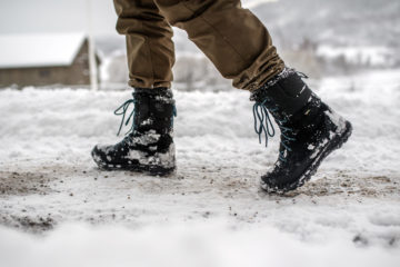 Ulkoilija kävelee talvimaisemassa nastakengät jalassa